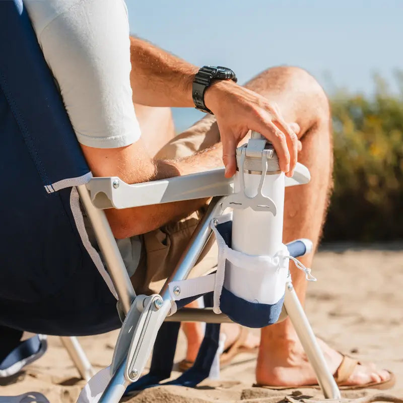 Close-up of a white water bottle placed in the mesh cup holder of a Nautical Blue Backpack Beach Chair.