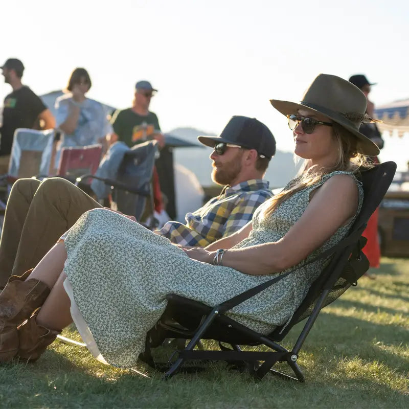 Couple relaxes in aged fatigue Everywhere Chair 2 at an outdoor event, enjoying the sunset.