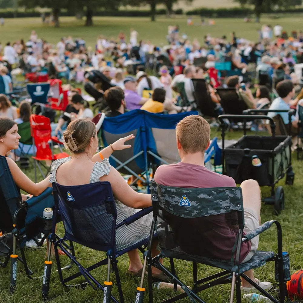 Two concert goers sitting in freestyle rocker elite chairs at a venue.
