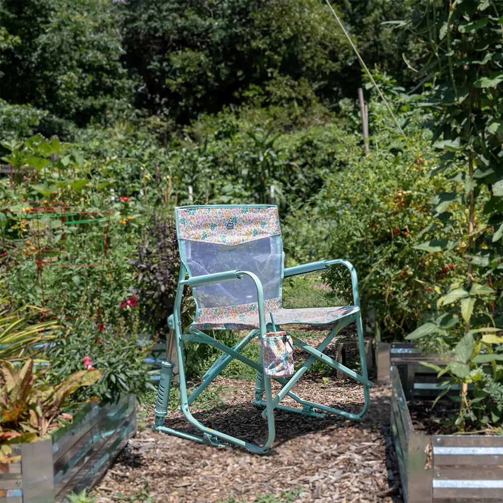 A teal sundress freestyle rocker elite chair surrounded by a garden setting.