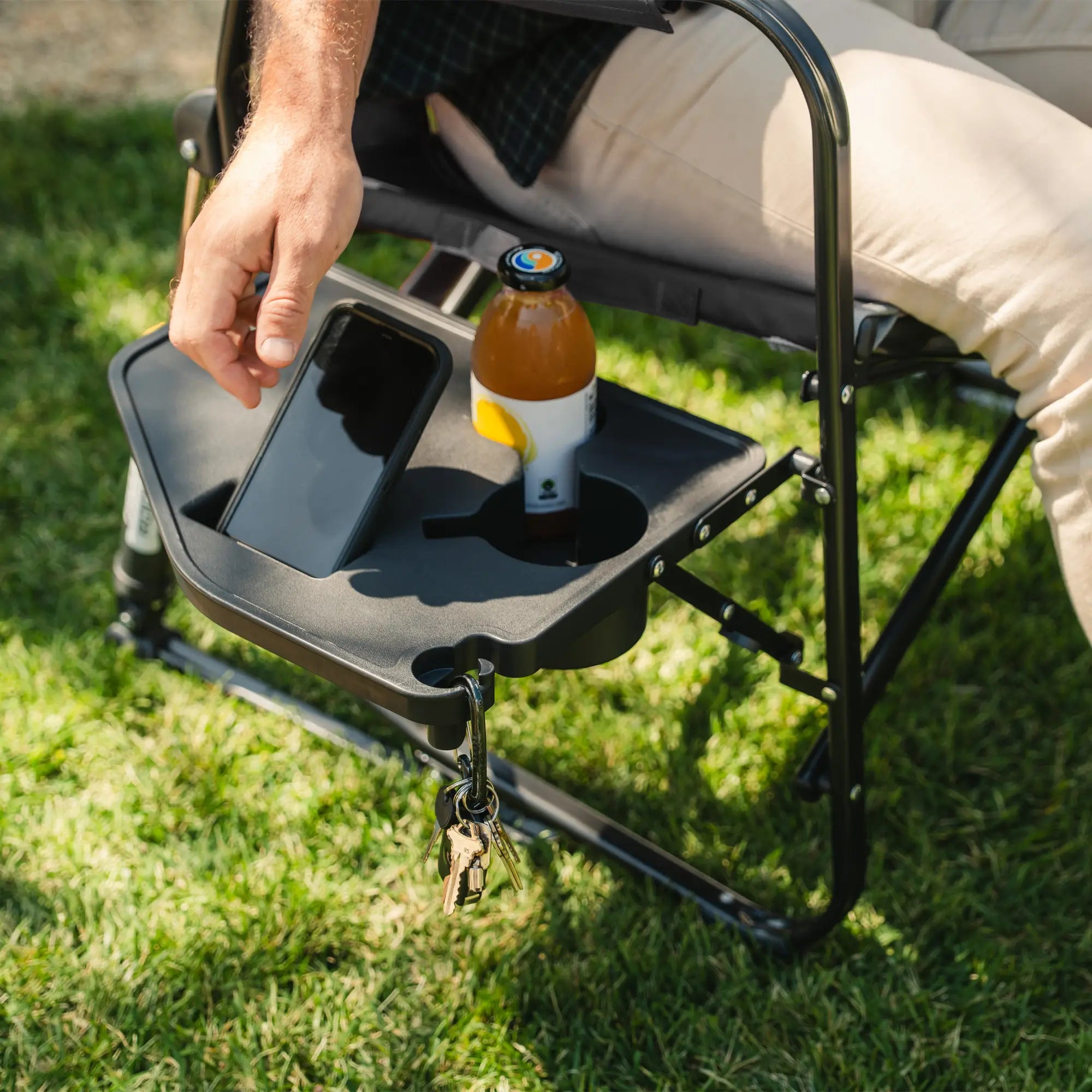 A man grabbing for his phone that is positioned in the side table of a freestyle rocker xl with side table.