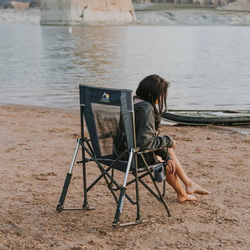 Woman relaxing on an indigo RoadTrip Rocker at the beach near a kayak.
