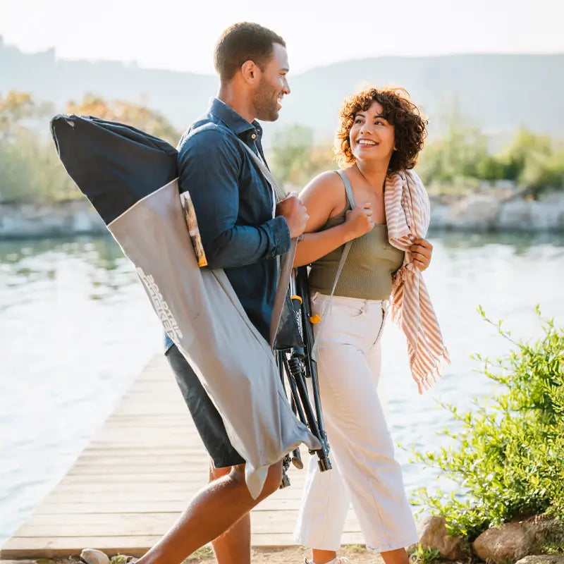 Couple walking near a dock with the RoadTrip Rocker folded in its carry bag.