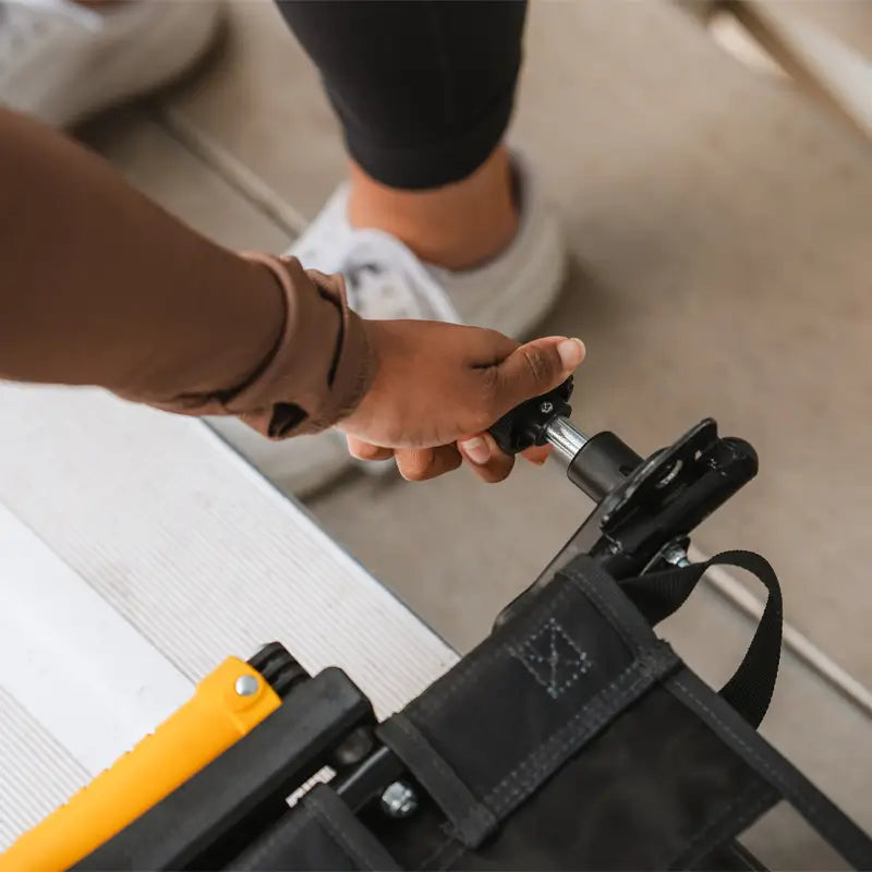 Close-up of a hand tightening the clamp on the dark charcoal Stadium Rock-Cliner.