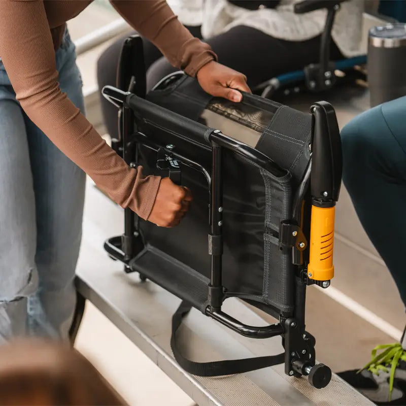 Woman folding up the dark charcoal Stadium Rock-Cliner for transport.