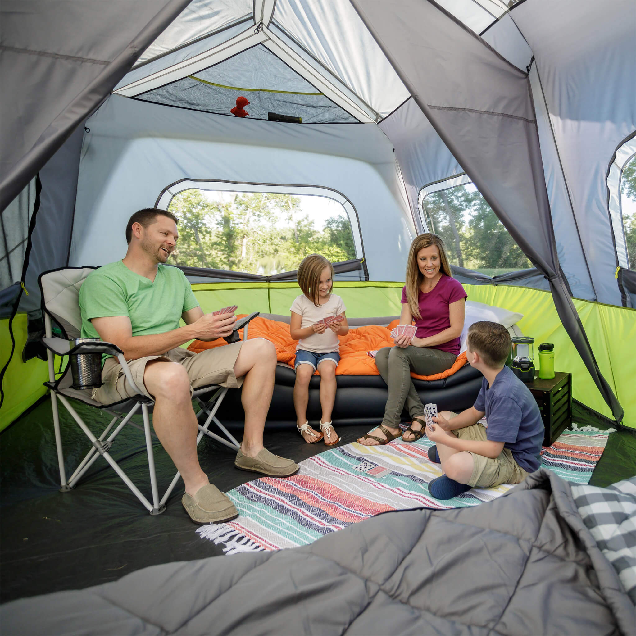 Family enjoying time inside the CORE 10 person instant cabin tent with screen room in gray and green, offering durable weather protection and comfort.