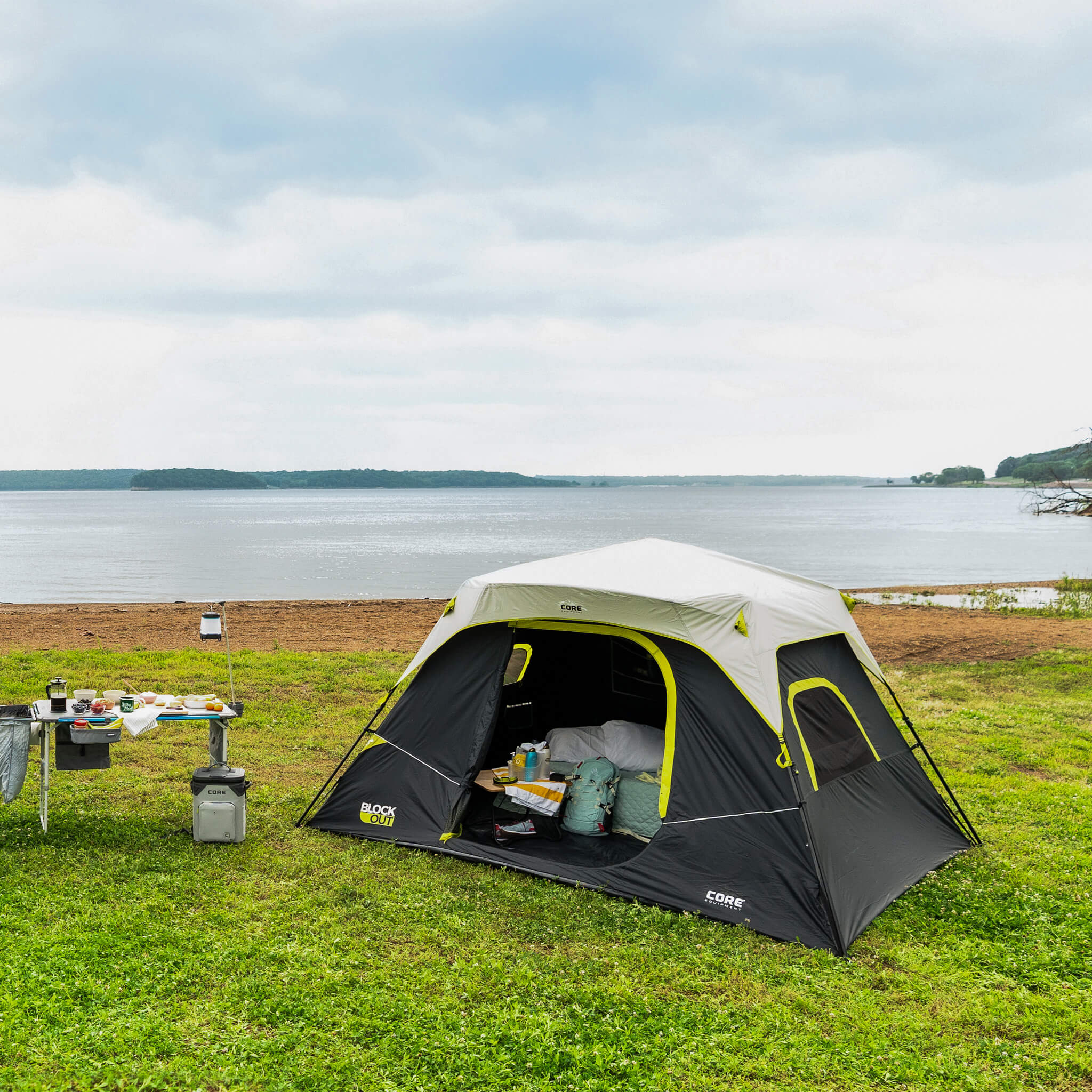 CORE 6 person Blockout instant cabin tent set up lakeside, ideal for camping with fast setup, shade, and dark interior.
