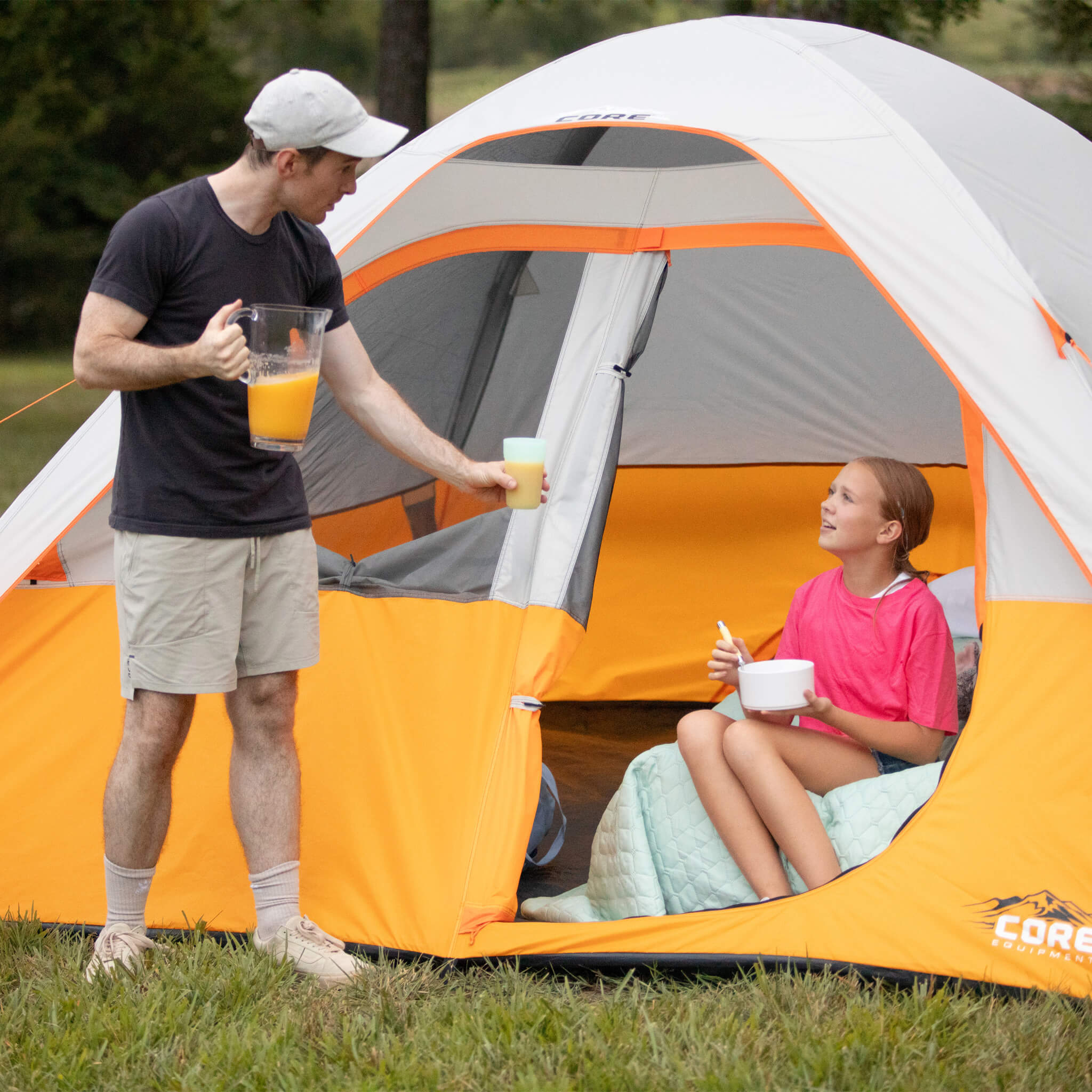 CORE 6 person dome tent at campsite with father serving drinks to daughter inside tent, showing spacious entry and cozy setup.