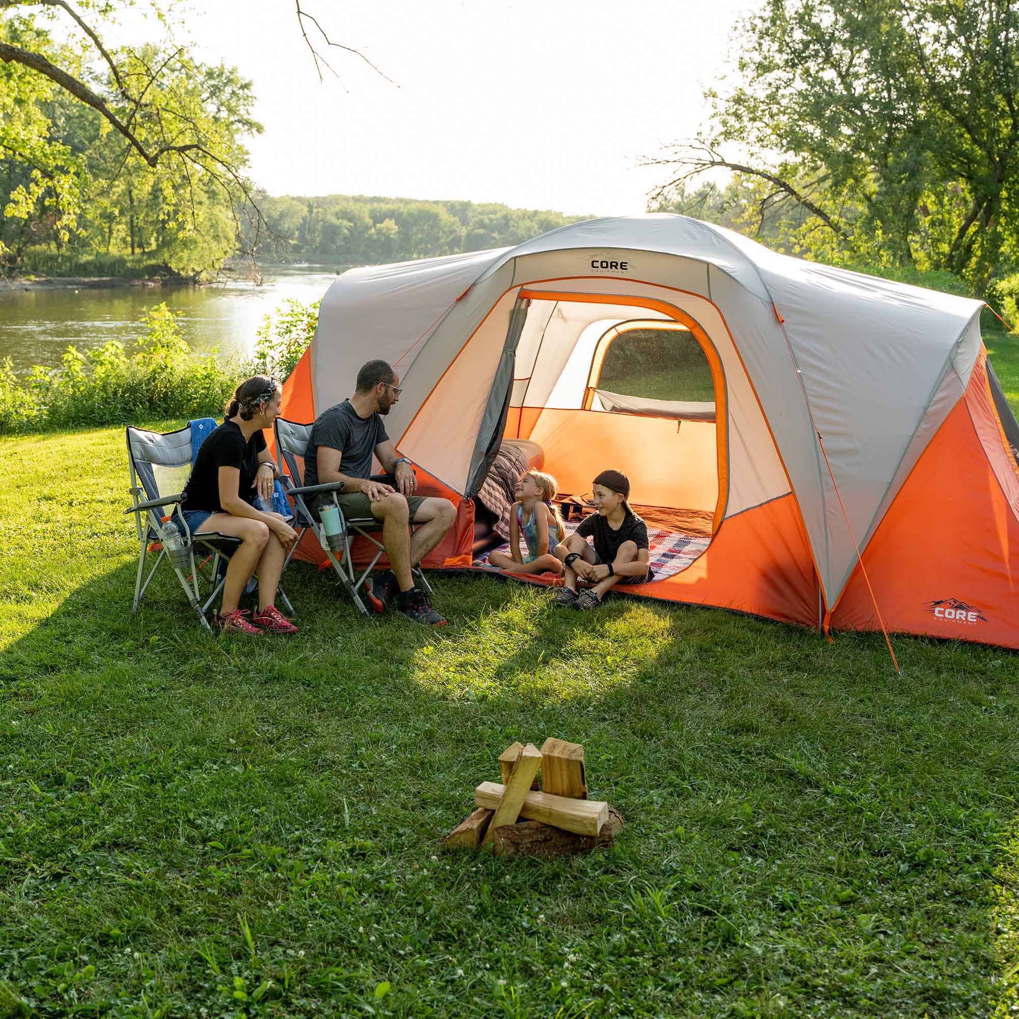 Family camping outdoors with a CORE 9 person dome tent in a grassy area.