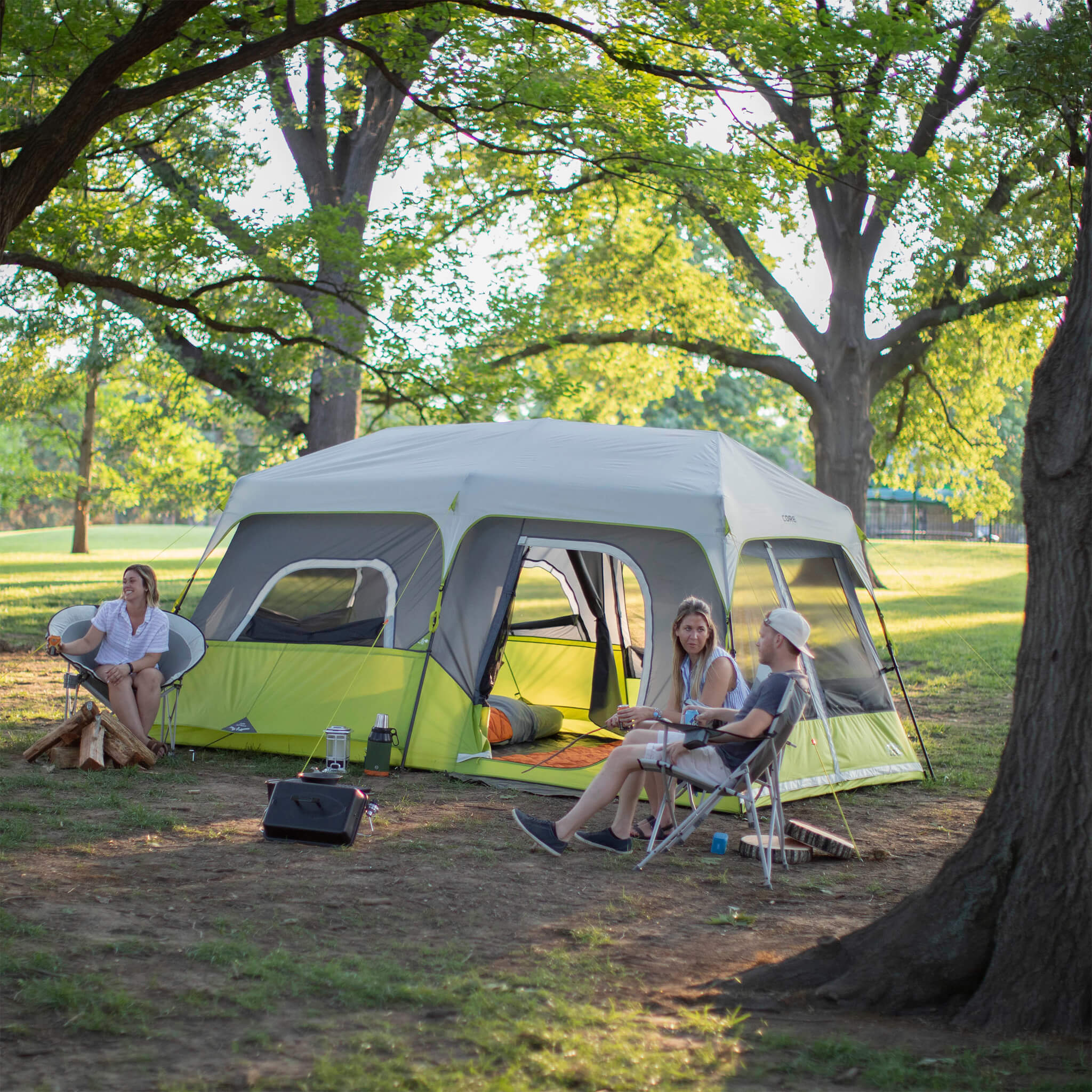 Campers relaxing beside the CORE 9 person instant cabin tent in gray and green, designed for fast setup and reliable weather protection.
