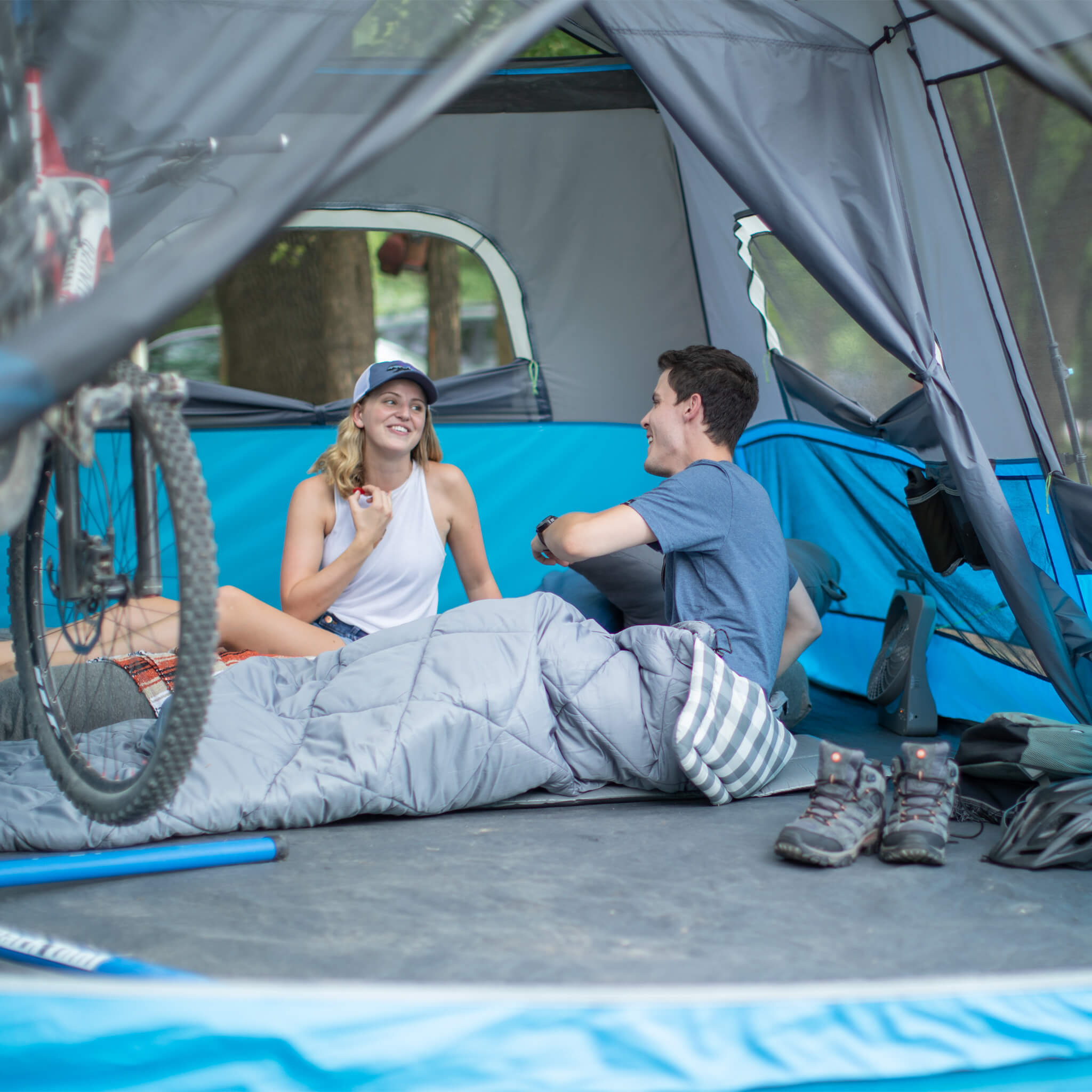 Friends enjoying time inside the CORE 9 lighted person instant cabin tent in blue and gray, offering durable weather protection and comfort.