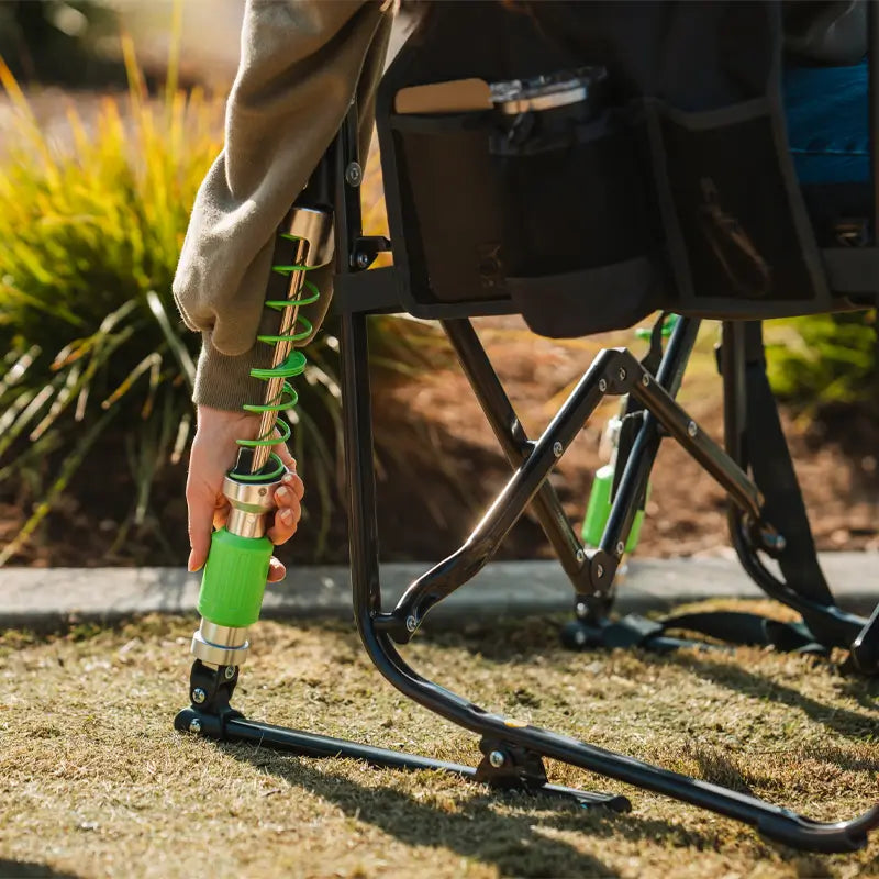 Woman adjusts the green shock-absorbing leg of her Adjustable Rocker while seated outside.