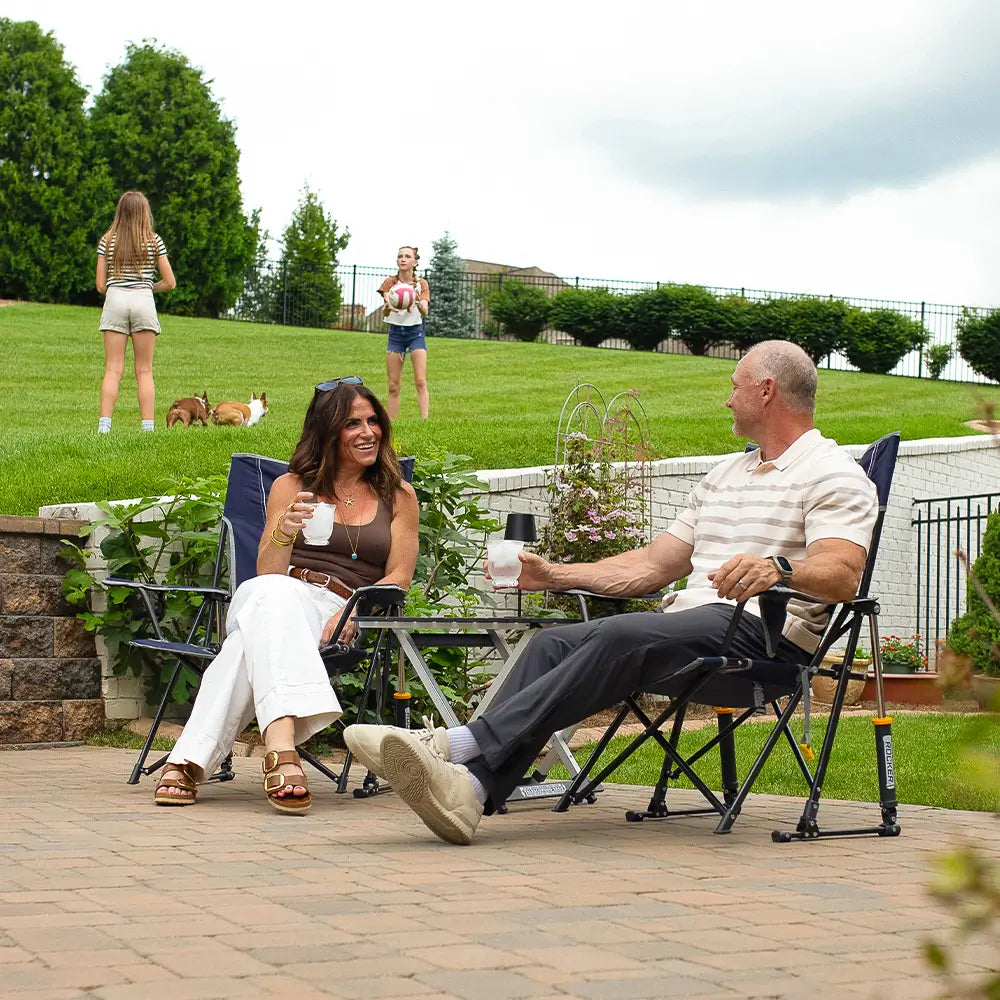 A couple sitting in two comfort pro rocker chairs in their backyard. 