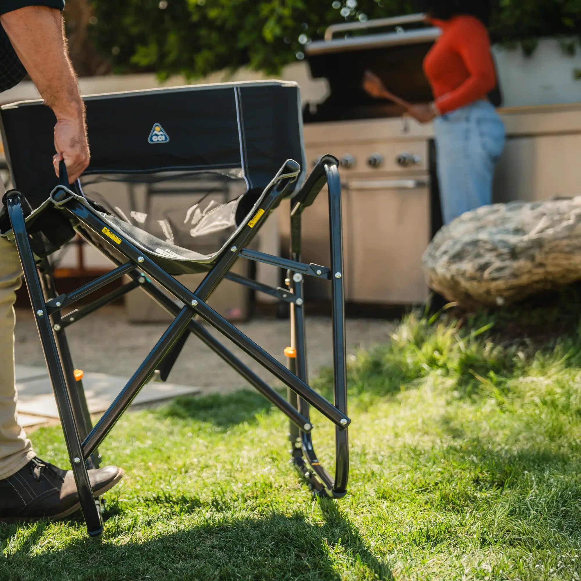 A man folding a black freestyle rocker chair by pulling on the eazy folding technology handle on the seat. 