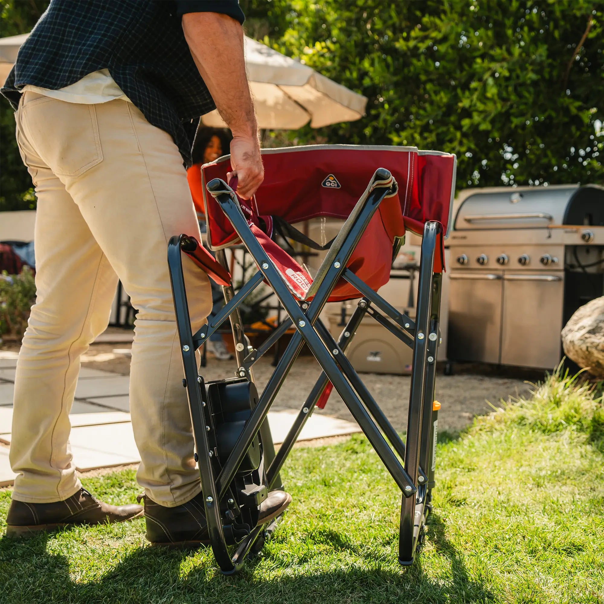 A man folding up a freestyle rocker xl with side table by using the easy fold handles on the seat of the chair. 