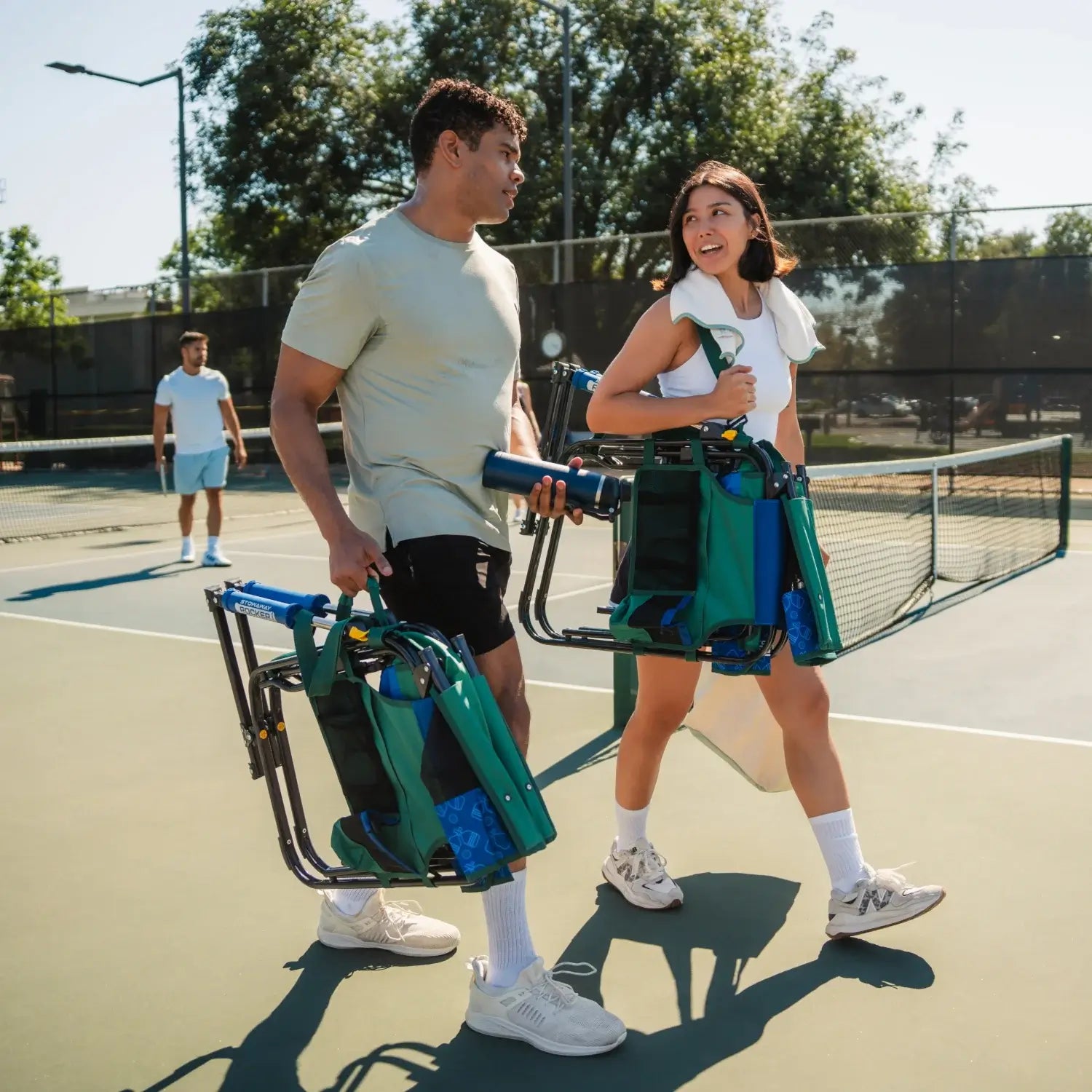 Two people carrying the pickleball stowaway rocker with shoulder straps and carry handle. 