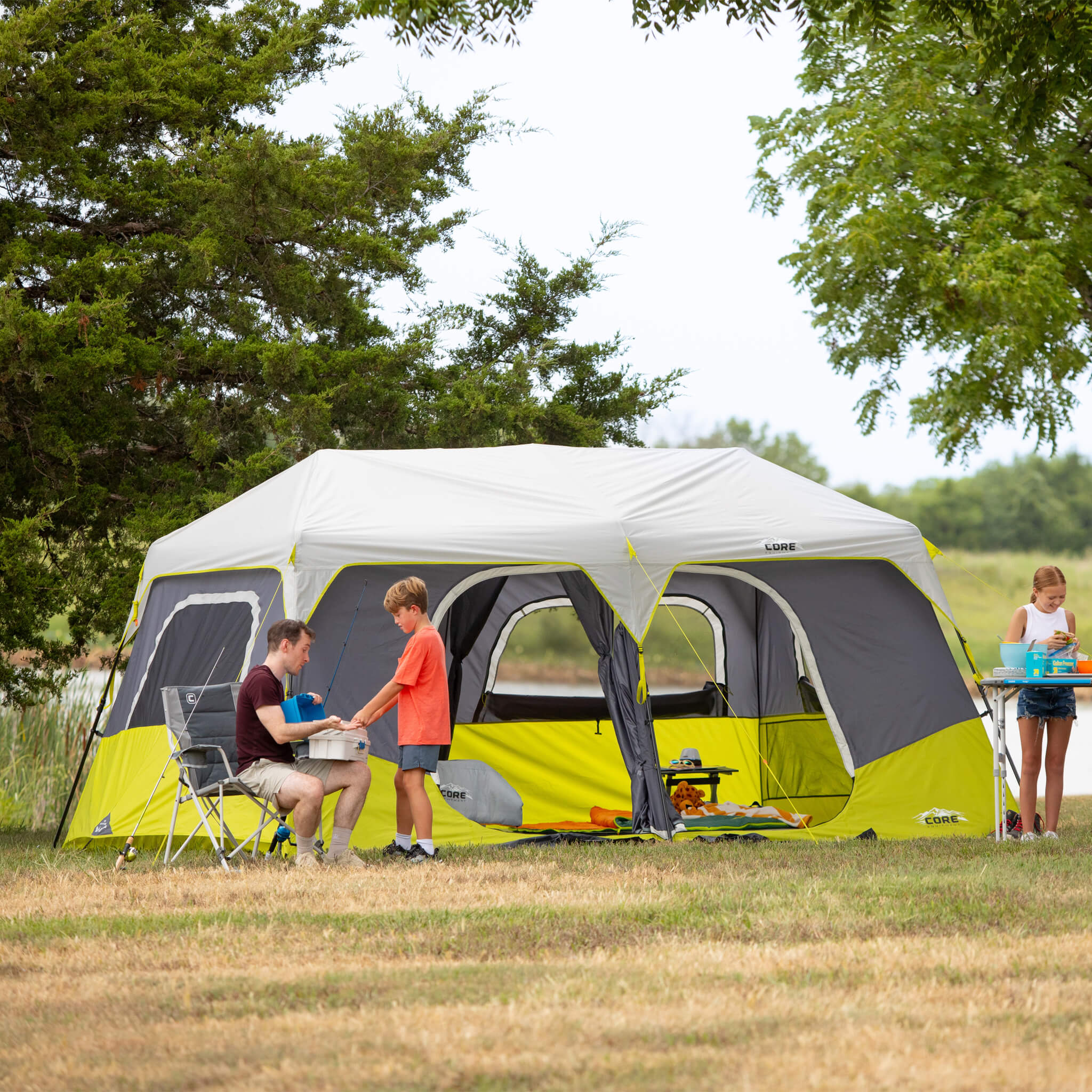 Family camping beside CORE 10 person instant cabin tent, showing spacious outdoor setup and easy access doors.
