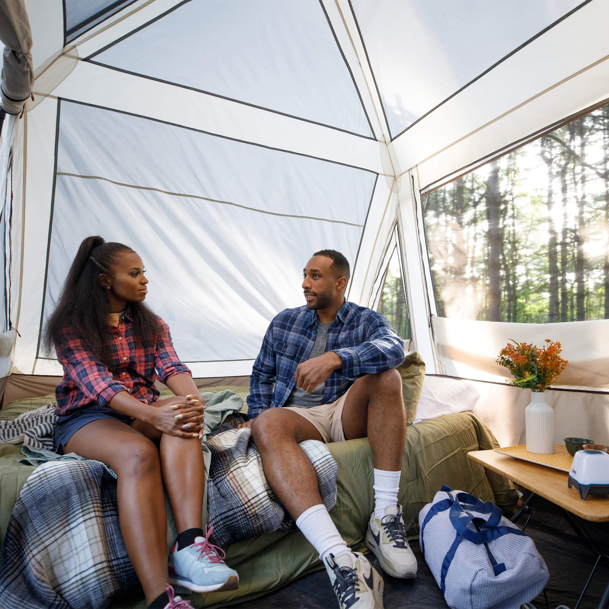 Campers sitting inside CORE 6 person instant pyramid tent with tall ceiling, mesh windows, and spacious living area.